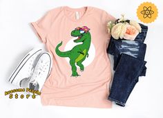 All T-Shirt apparel are printed using direct-to-garment (also known as DTG). In addition, our inks are water based and eco-friendly. This makes the feel much softer than traditional screen printed shirts, but just as durable. Dinosaur Shirt, Cute Dinosaur, Dinosaur Birthday, Dinosaur Lover, T Rex Shirt, Birthday Gift Idea, Dinosaur Mom, Unisex, Dinosaur Party **All sales are final and we don't accept returns. If we made a mistake we will send a replacement.** The best way to get the size you nee Green Dinosaur Print T-shirt For Summer, Fun Summer T-shirt With Dinosaur Print, Green Dinosaur Print Summer T-shirt, Summer Dinosaur Print Top For Birthday, Dinosaur Print Tops For Summer Birthday, Summer Birthday Top With Dinosaur Print, Summer Birthday Tops With Dinosaur Print, Green Dinosaur Print Top For Spring, Green Dinosaur Print Tops For Spring