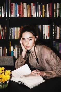 a woman sitting at a table in front of a book shelf with books on it