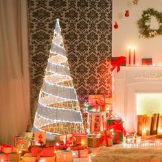 a christmas tree surrounded by presents in front of a fireplace with lit candles on it