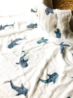 an unmade bed with white sheets and blue whale designs on the comforter, next to a brown teddy bear