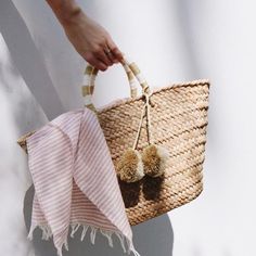 Our woven tote bag is made of natural seagrass and features matching raffia poms poms. It's roomy enough for your beach towel, sunglasses and more. Perfect for a trip to the beach or market. #wovenbag #beachbag #beachtote Chic Beach Outfit, Natural Handbags, Chic Style Inspiration, Summer Clutch, Luxury Sustainable, Woven Tote Bag, Straw Tote, St Tropez, Beach Accessories