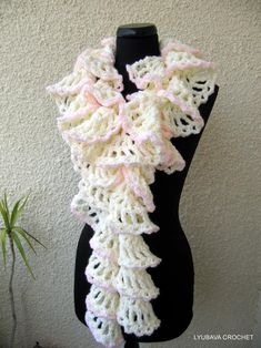 a white crocheted scarf hanging on a mannequin's dummy next to a potted plant