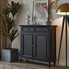 a black cabinet sitting next to a lamp on top of a wooden floor in a living room