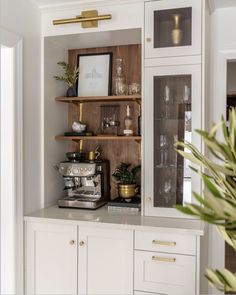 a kitchen with white cabinets and gold trim on the glass doors, brass knobs