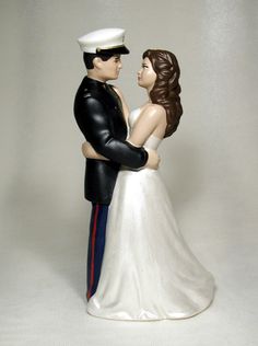 a bride and groom figurine standing next to each other on a white background