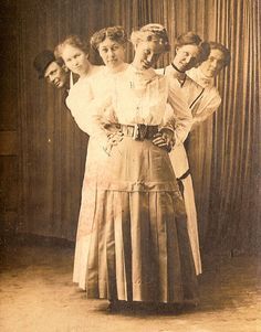 an old black and white photo of four women standing in front of a curtain with their arms around each other