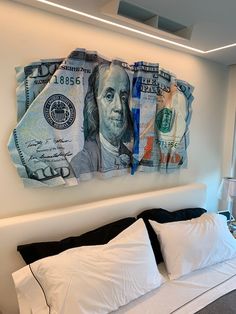 a bed that has some money on the wall above it and pillows in front of it