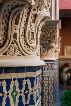 an intricately designed column in the middle of a building with blue and white tiles