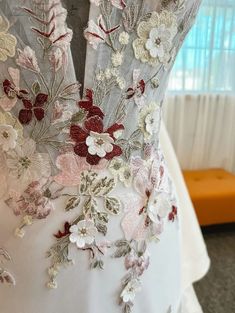 the back of a wedding dress with flowers and leaves on it's chest,