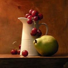 a white pitcher filled with grapes next to a green apple and some red cherries