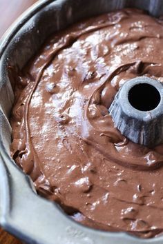 a cake pan filled with chocolate frosting on top of a wooden table