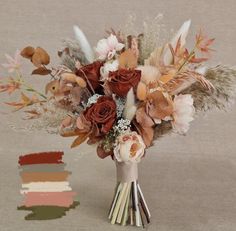 a vase filled with flowers and feathers on top of a table next to color swatches