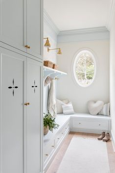 a room with white cabinets and a large round window in the corner, along with a rug on the floor