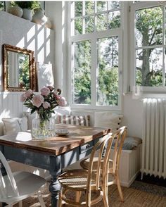 a dining room table and chairs in front of two large windows with white trimmings