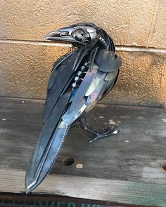 a metal bird sitting on top of a wooden floor