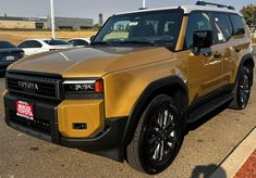 a gold colored land rover is parked in a parking lot with other cars behind it