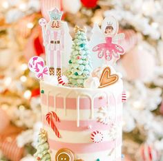 a decorated christmas cake sitting on top of a table next to a white and red tree