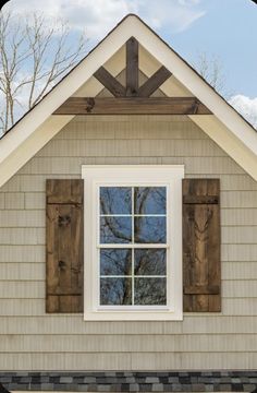 an open window on the side of a house with wood shutters and shingles