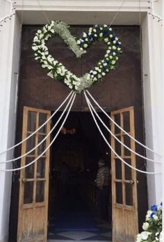 the entrance to a building decorated with white and blue flowers in the shape of a heart