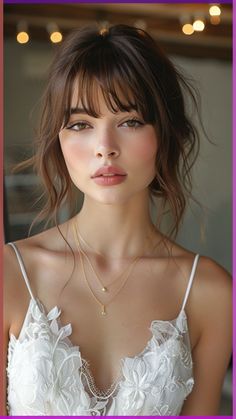 a young woman wearing a white dress and gold necklace with flowers on her chest, looking at the camera