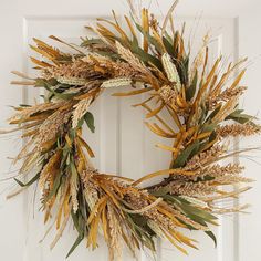 a wreath made out of dried grass and leaves is hanging on the front door handle