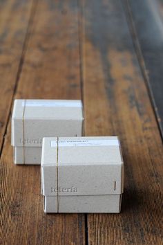 two white boxes sitting on top of a wooden table