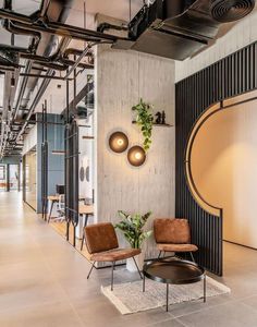 two chairs and a table in a room with exposed pipes on the wall behind them