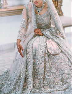 a woman in a wedding dress sitting on a chair wearing a tiara and veil