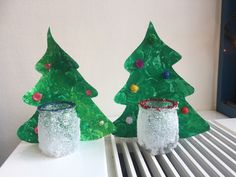 two plastic christmas trees sitting on top of a white table next to a radiator