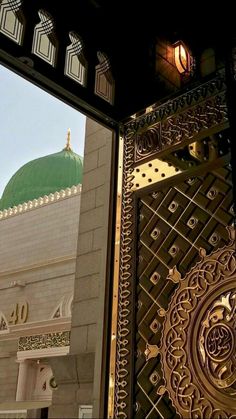 an ornate metal door with a green dome in the background and light shining on it