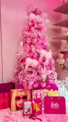 a pink christmas tree is surrounded by barbie dolls and other items in front of it