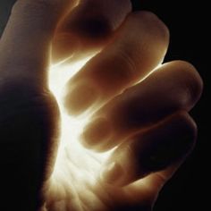 a person's hand holding something in the air with light coming out of it