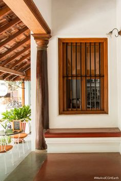 a wooden window sitting on the side of a white wall next to potted plants