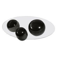 three black balls sitting on top of a white plate