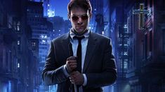 a man in a suit and tie with sunglasses on his head standing in the middle of a city at night