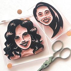 two cut outs of people are sitting next to a pair of scissors