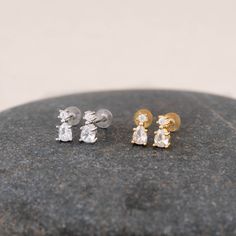 three pairs of earrings sitting on top of a rock