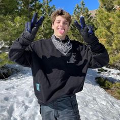 a young man standing in the snow with his hands up and smiling at the camera