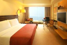 a hotel room with a large bed, desk and television in front of a window