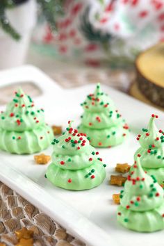 small green frosted christmas trees on a white platter with candy canes and sprinkles