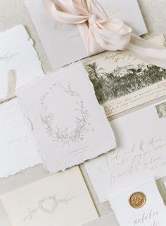 the wedding stationery is laid out on top of each other and tied with a pink ribbon