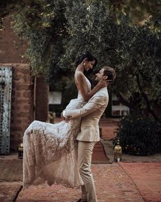 a man in a suit is holding a woman on his back and she is wearing a wedding dress