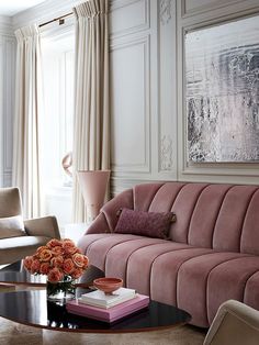 a living room filled with furniture and flowers on top of a coffee table in front of a window