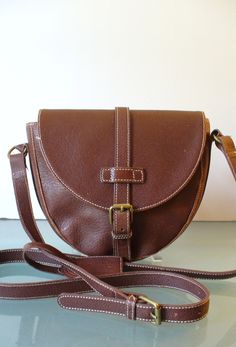 This bag is in great vintage condition. No rips stains or odors aside from some very light soiling to the lining in the bottom of the bag. It features one large compartment inside with a zipper pocket.  Long, adjustable strap allows it to be worn cross body. Measures 8.5"x 8.5"x 32.5" Strap 24" Adjustable to shorter lengths. Please measure carefully and feel free to ask more questions as there are  no refunds or exchanges. Lot 26 r-5 Vintage Brown Flap Shoulder Bag, Vintage Flap Shoulder Bag For Everyday, Brown Leather Bag With Lined Interior, Vintage Saddle Bag With Removable Pouch, Vintage Brown Saddle Bag With Detachable Strap, Vintage Brown Saddle Shoulder Bag With Adjustable Strap, Vintage Saddle Bag With Detachable Strap For Daily Use, Vintage Saddle Bag Satchel With Adjustable Strap, Vintage Satchel Saddle Bag With Adjustable Strap