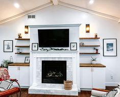 a living room with a fire place and shelves on either side of the fireplace that has a flat screen tv above it