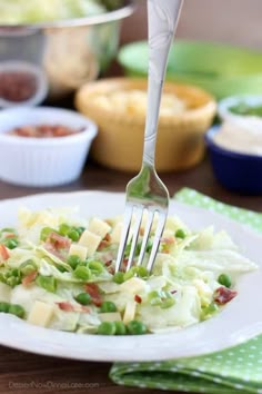 a fork that is on top of a plate with some food in bowls behind it