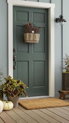 a green door with two planters on the side and one potted plant in front