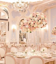 a table set up for a wedding with flowers in vases and candles on the tables