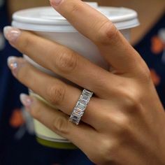 a woman's hand holding a coffee cup with her engagement ring on top of it