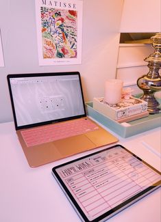 an open laptop computer sitting on top of a white desk next to a clipboard